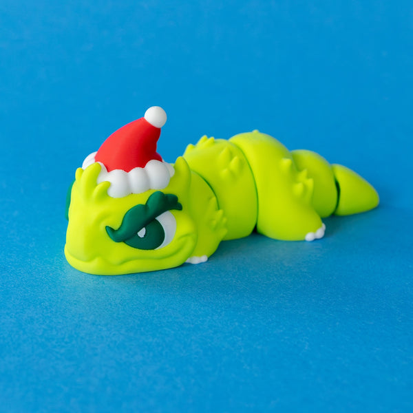Grump the Humbug Chonk, a green dragon in a red Santa hat with a grumpy frown, front view