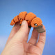 Orange platypus fidget toy with a brown bill, arched across fingers