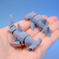 Two grey hammerhead shark fidget toys shown together in a hand