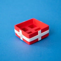 Empty red four-slot gift box clicker base from above, showing the four sockets