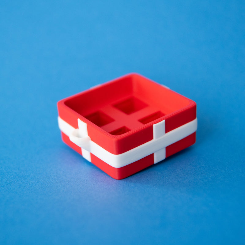 Empty red four-slot gift box clicker base from above, showing the four sockets