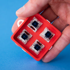 Red four-slot gift box base with switches, held in a hand