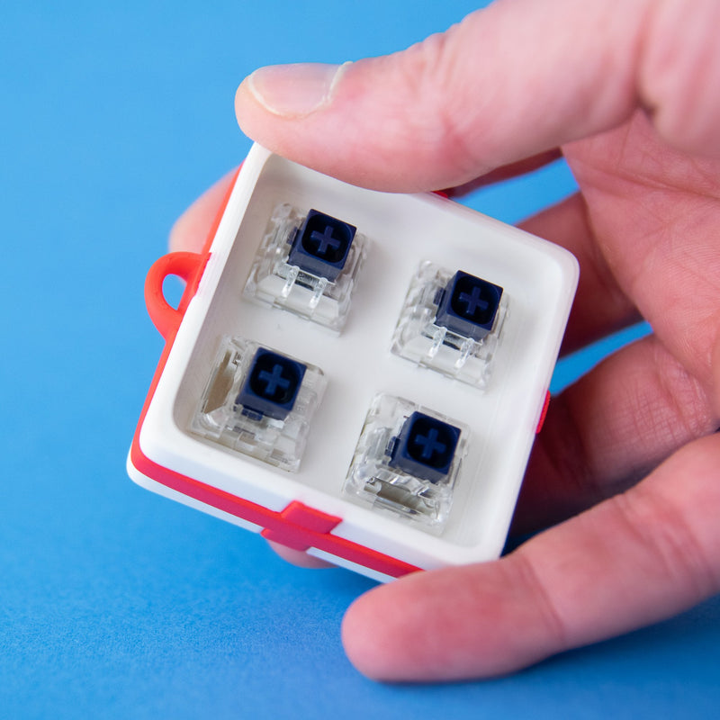 White four-slot gift box base with switches, held in a hand