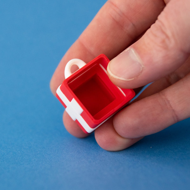 Red single gift box clicker base held between finger and thumb