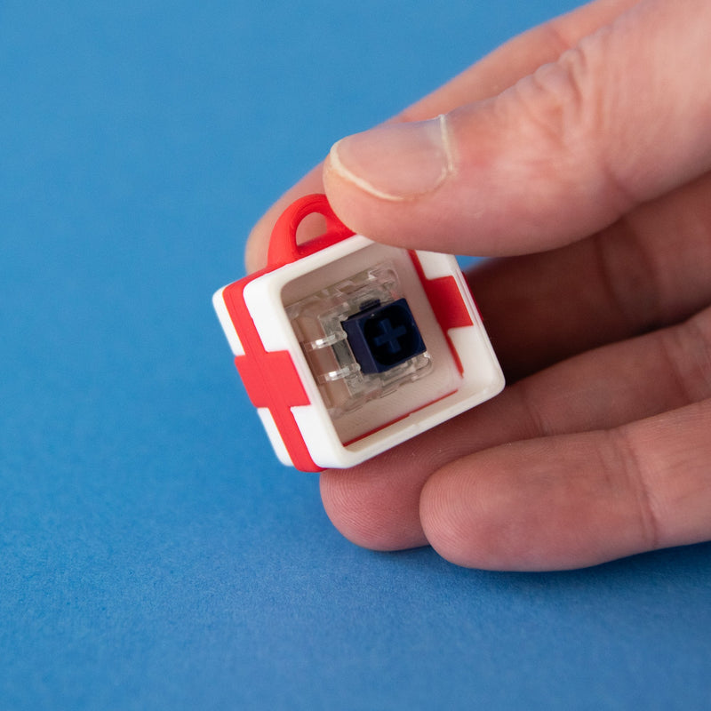 White single gift box base with a switch, held in fingers to show its size