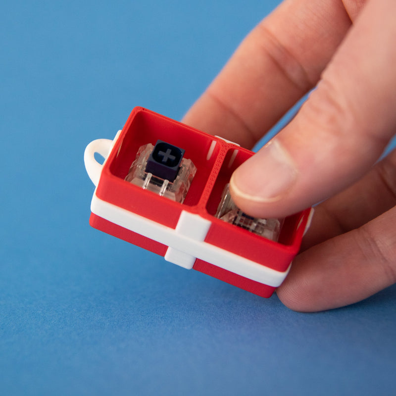Red two-slot gift box base with switches, held in a hand