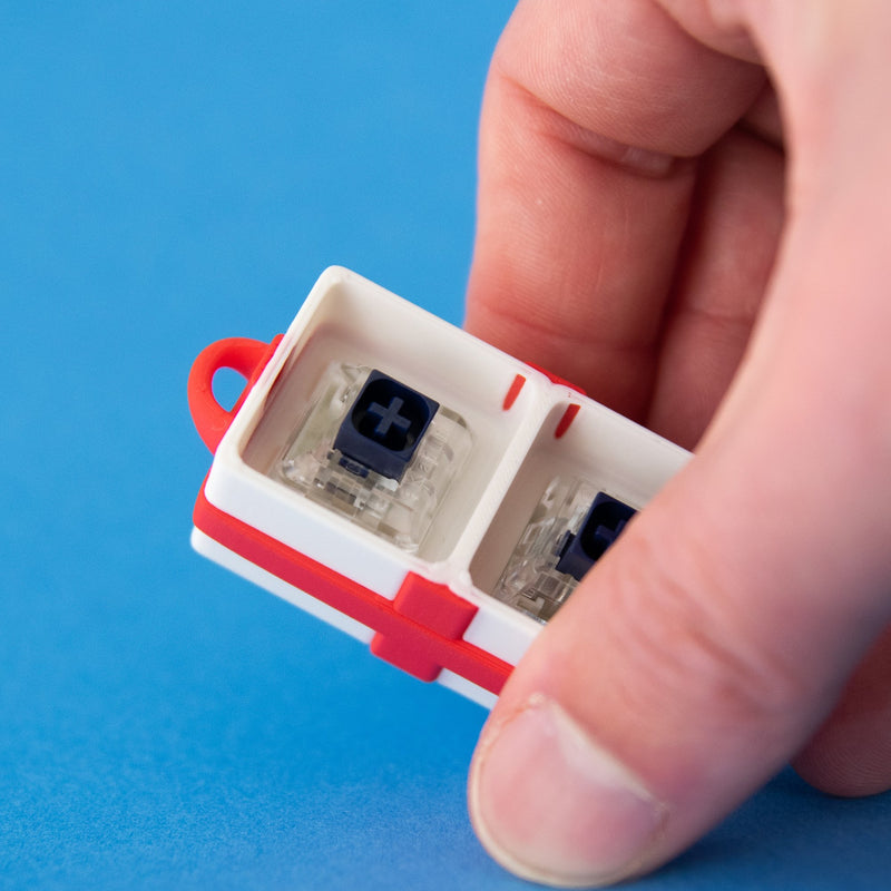 White two-slot gift box base with switches, held in a hand
