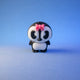 Dottie penguin figurine standing alone with a pink bow on her head against a blue background.