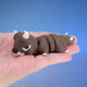 Brown bull-themed chonk dragon fidget toy with white horns, curled in a hand