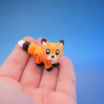 Orange fox fidget toy with black paws and a white-tipped tail, standing on fingers