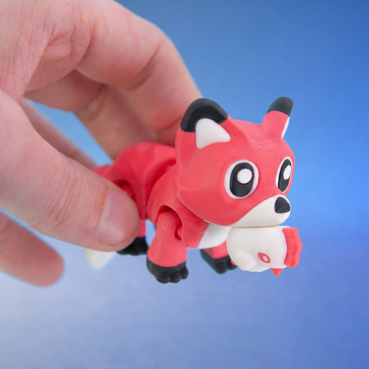 Red fox figurine holding a small chicken toy in its mouth