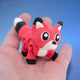 Red fox figurine with black paws and a white belly, standing alert