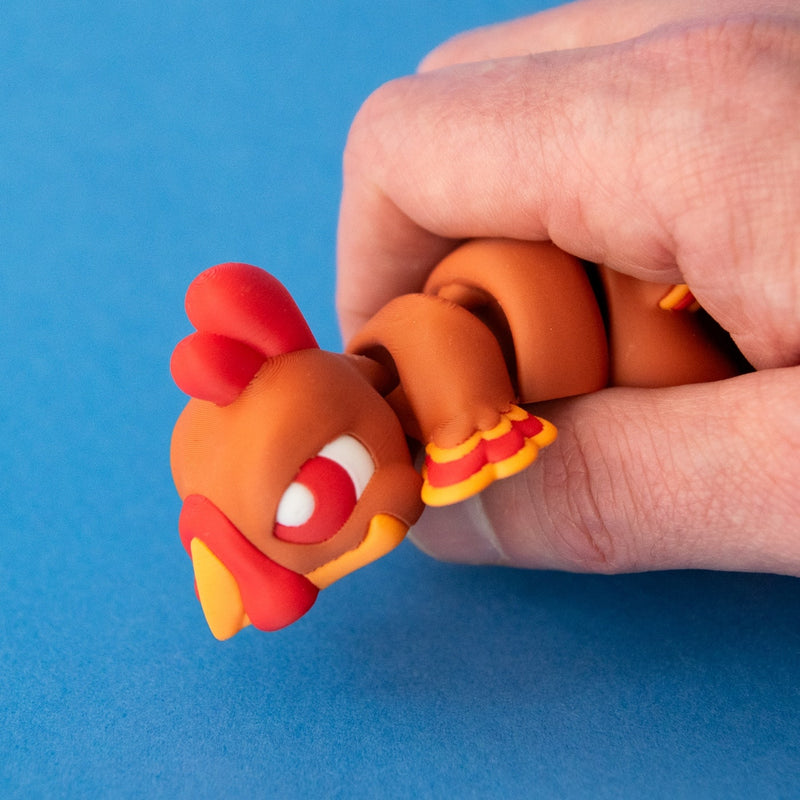 A hand bending Gobb the Turkey Beastchonk to show movement around his head and body.