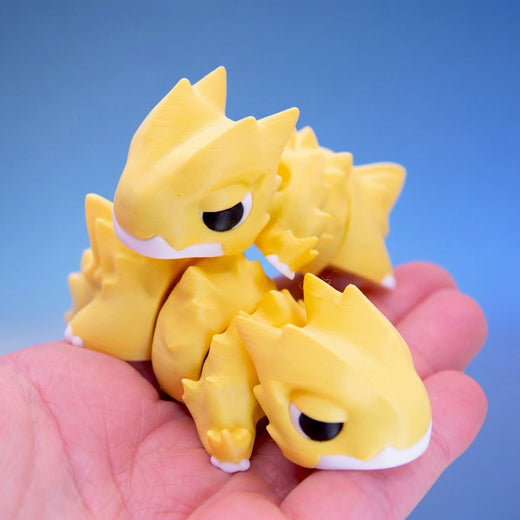 Three yellow chonk dragon fidget toys grouped together in a hand