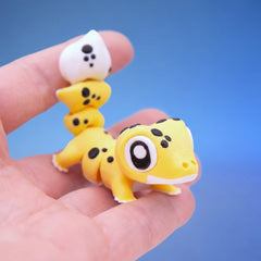 Yellow leopard gecko fidget toy with black spots, walking across fingers