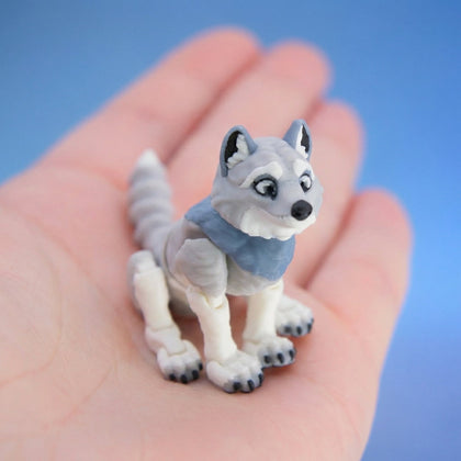 Grey and white wolf figurine wearing a blue scarf, standing alert