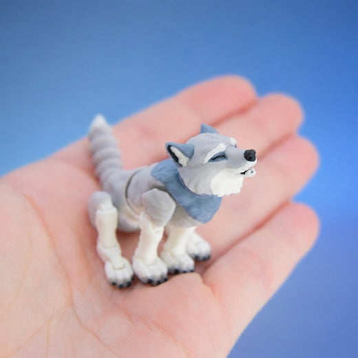Grey and white wolf figurine with its head tilted back, howling