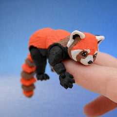 Close-up of the red panda fidget toy's face and front paws, with white and brown markings