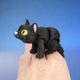 Black cat figurine with yellow eyes and pink ears, crouched low
