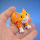 Orange and white cat figurine with yellow eyes, crouched and looking up