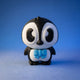 Ned penguin figurine standing alone with a blue bow tie against a blue background.