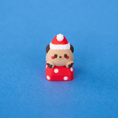Nutmeg the Santa puppy keycap in a red Santa hat, paws on a spotty red present, front view