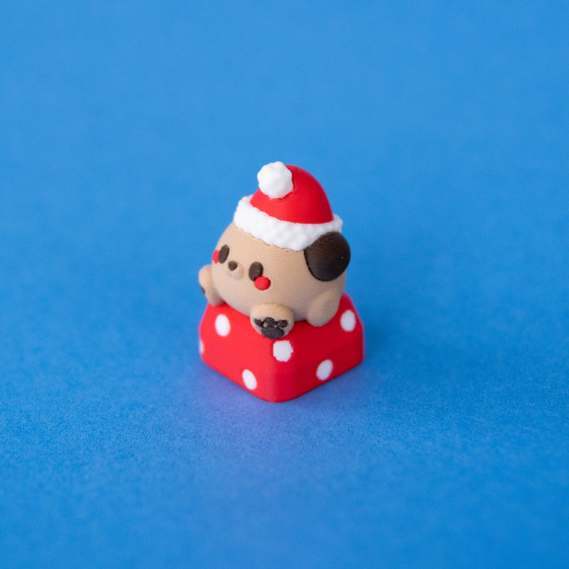 Nutmeg the Santa puppy keycap, three-quarter view from the left