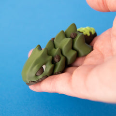 Oke held in a hand, with his face, acorns and leaf-shaped body segments visible.