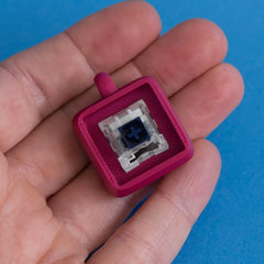 Plum keycap clicker base with switch in hand view.