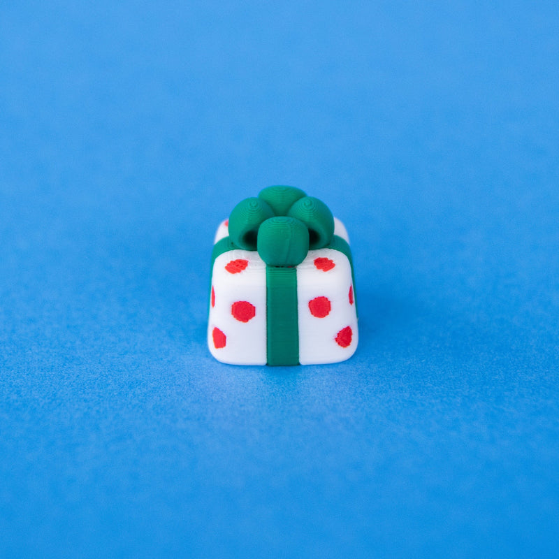 Polka the spotted present keycap, white with red spots and a green bow, front view
