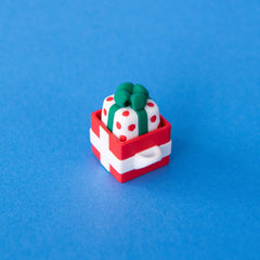 Polka spotted present keycap sitting in a red gift box clicker base