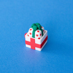 Polka spotted present keycap sitting in a white gift box clicker base