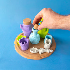Hand placing a cork in the blue healing bottle