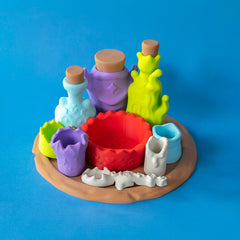 Potion Kit display set with bottles, cups, red mixing bowl and spoon on a wooden-look serving plate, front view