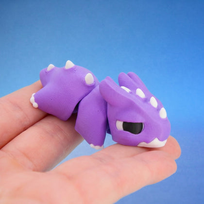 Purple chonk dragon fidget toy with white horns and spiky ridges, curled in a hand