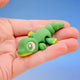Rex the Dino Hatchling in the Classic style - a smooth green dinosaur fidget toy with a yellow chin, curled in a hand