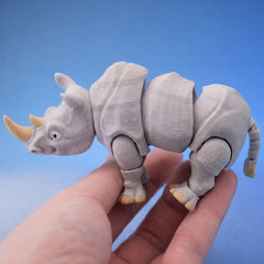 Grey rhino figurine seen from the side, showing its articulated legs and tail