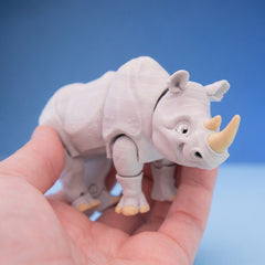 Grey rhino figurine with a tan horn, standing in a hand