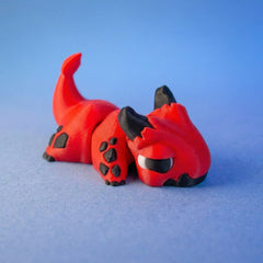 Red and black imp dragon fidget toy curled compactly in a hand