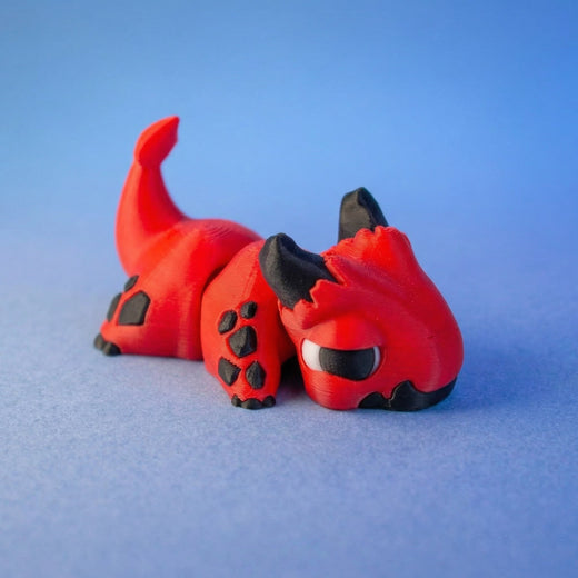 Red and black imp dragon fidget toy curled compactly in a hand