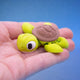 Yellow-green sea turtle fidget toy with a brown shell, resting in a hand