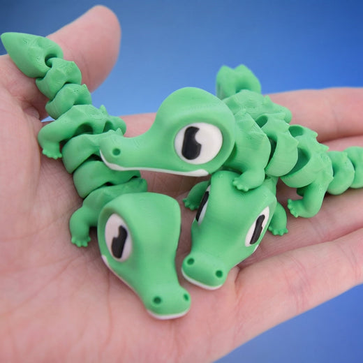 Three green crocodile fidget toys grouped together in a hand