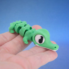 Green crocodile fidget toy with a segmented body, crawling across fingers