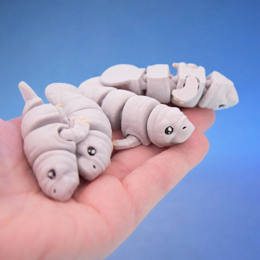 Two grey manatee fidget toys shown together in a hand