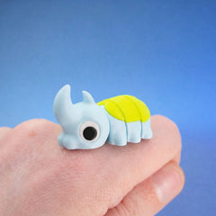 Sky-blue horned beetle fidget toy with a neon-green shell, resting on a fingertip