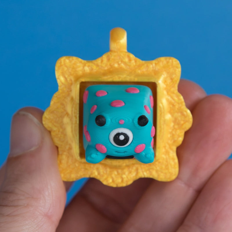 Spotto the monster in gold frame keycap clicker front view.