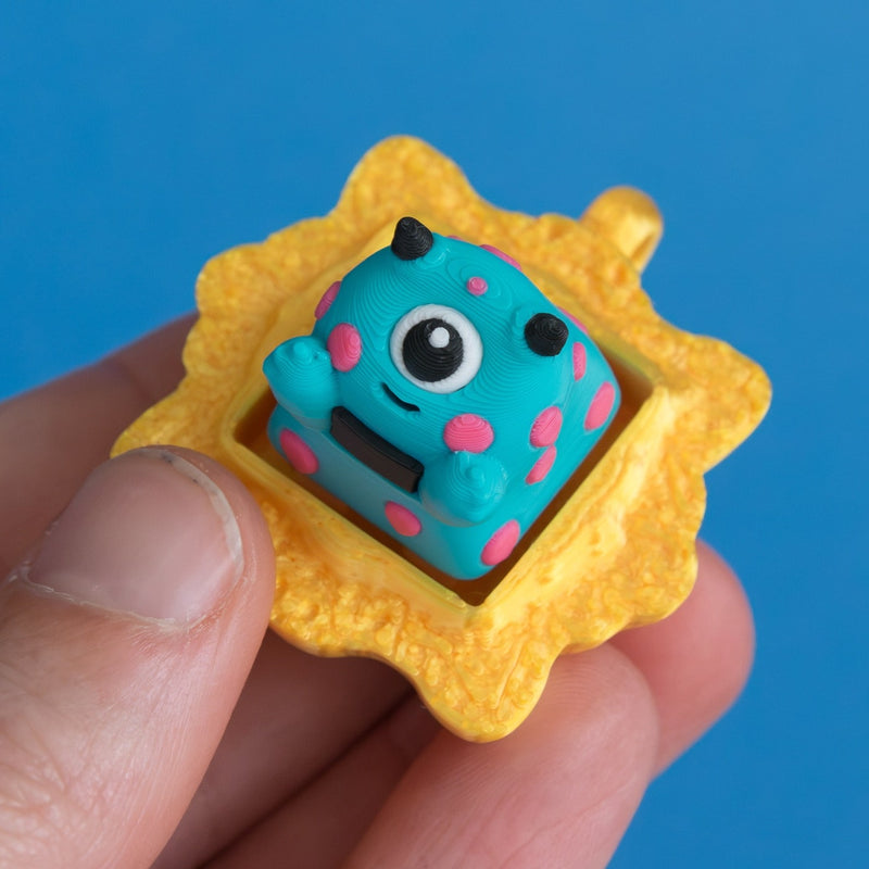 Spotto the monster in gold frame keycap clicker three quarter view.