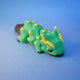 Green Christmas-tree-themed chonk dragon fidget toy with yellow ornament-style dots, resting on its side
