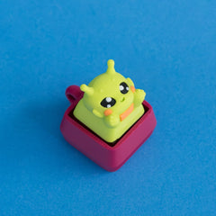 Zibby the bright green alien keycap on plum clicker base.