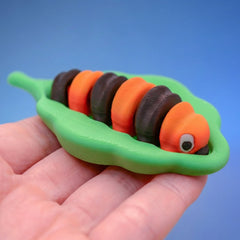 Two orange and black striped caterpillar fidget toys face to face in a hand.